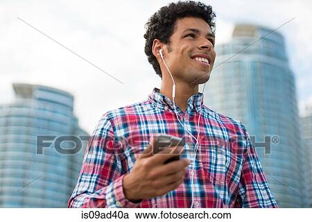 Stock Image - Man listening to music on mobile phone. Fotosearch