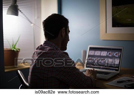 Stock Image - Man sitting at desk using laptop. Fotosearch