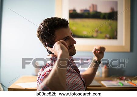 Man sitting at desk using smartphone View Large Photo Image Stock Image - Man sitting at desk using smartphone. Fotosearch