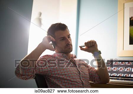 Man sitting at desk using smartphone View Large Photo Image Stock Photo - Man sitting at desk using smartphone. Fotosearch