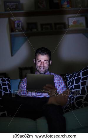 Man sitting on sofa using digital tablet View Large Photo Image Picture - Man sitting on sofa using digital tablet. Fotosearch