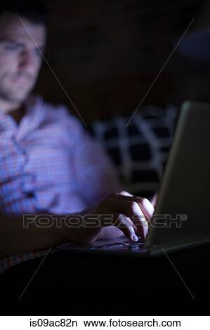 Man sitting on sofa using laptop View Large Photo Image Picture - Man sitting on sofa using laptop. Fotosearch