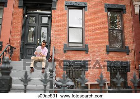 Man sitting on step using digital tablet View Large Photo Image Stock Image - Man sitting on step using digital tablet. Fotosearch