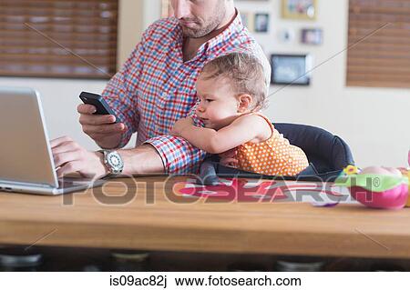 Man working at kitchen counter with baby sitting beside View Large Photo Image Stock Image - Man working at kitchen counter with baby sitting beside. Fotosearch
