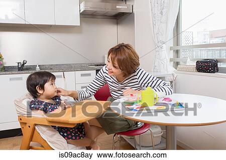 Mother chatting to baby at dining table View Large Photo Image Stock Photo - Mother chatting to baby at dining table. Fotosearch