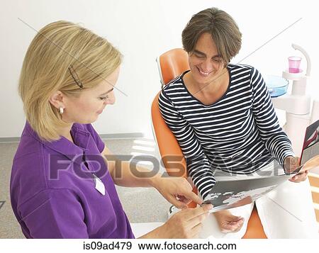 Patient looking at brochure for dental implants View Large Photo Image Stock Photo - Patient looking at brochure for dental implants. Fotosearch