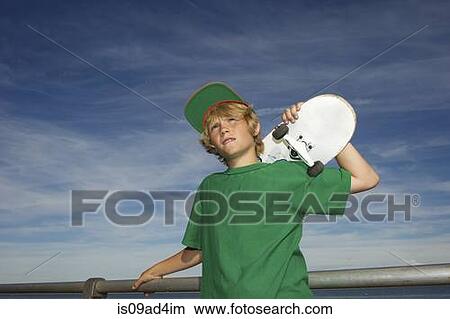 Picture - Portrait of boy holding skateboard over shoulder. Fotosearch