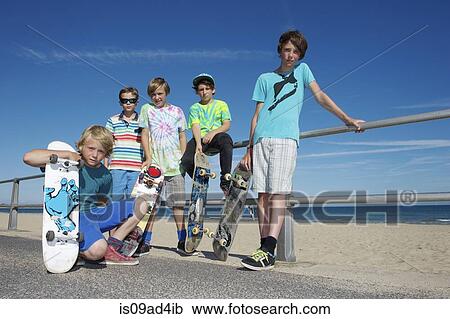 Stock Image - Portrait of five boys with skateboards at coast. Fotosearch