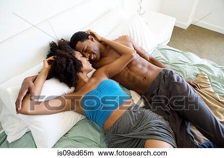 Portrait of young couple lying on bed View Large Photo Image Picture - Portrait of young couple lying on bed. Fotosearch