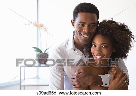 Stock Image - Portrait of young couple, man with arm around woman. Fotosearch