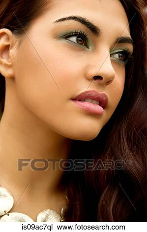 Stock Image - Portrait of young woman, wearing eye shadow, looking away. Fotosearch
