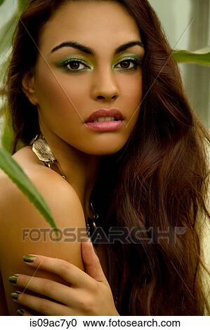 Stock Image - Portrait of young woman wearing green eye shadow and nail polish. Fotosearch