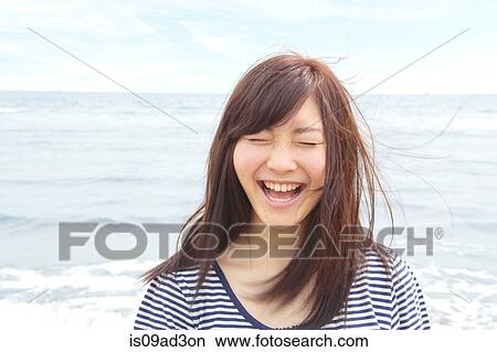Picture - Portrait of young woman with eyes closed, laughing. Fotosearch