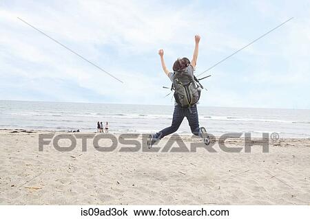 Rear view of woman jumping on beach View Large Photo Image Stock Image - Rear view of woman jumping on beach. Fotosearch