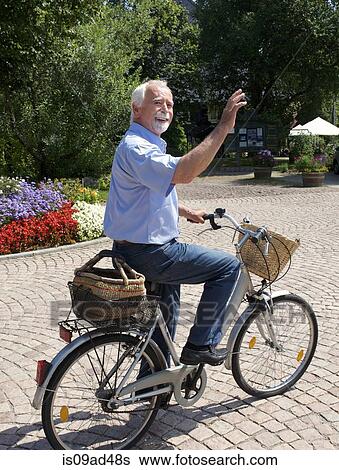 Stock Photograph - Senior man cycling through park. Fotosearch
