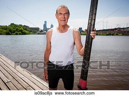 Stock Photograph - Senior man on pier holding oars. Fotosearch