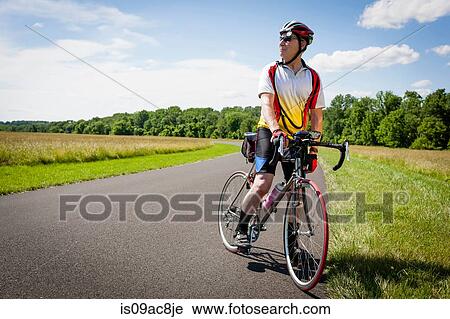 Stock Image - Senior man riding bicycle through countryside. Fotosearch