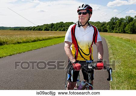 Stock Image - Senior man riding bicycle through countryside. Fotosearch
