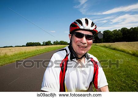 Stock Image - Senior man riding bicycle through countryside. Fotosearch