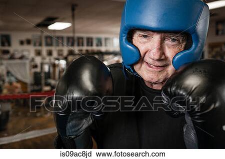 Stock Image - Senior man wearing boxing gloves and helmet. Fotosearch