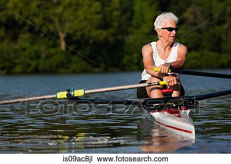 Stock Image - Senior woman rowing in rowing boat. Fotosearch