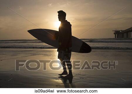 Surfer silhouetted on beach View Large Photo Image Stock Image - Surfer silhouetted on beach. Fotosearch