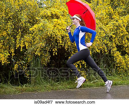 Teenage girl jogging with umbrella on road, Bainbridge Island, Washington, USA View Large Photo Image Stock Photo - Teenage girl jogging with umbrella on road, Bainbridge Island, Washington, USA. Fotosearch