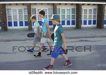 Stock Image - Three boys carrying skateboards. Fotosearch