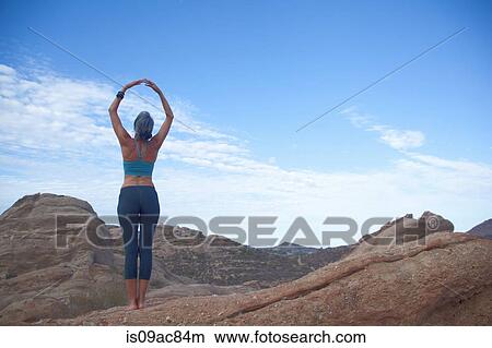 Picture - Woman doing yoga at Vazquez Rocks, hands together above her head. Fotosearch