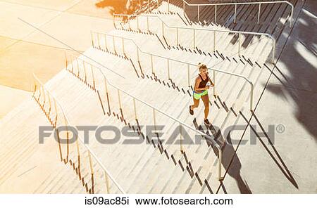 Stock Image - Woman running up stairs. Fotosearch