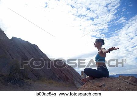 Stock Photograph - Woman sitting cross legged at Vazquez Rocks, meditating. Fotosearch
