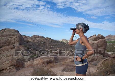 Woman standing at Vazquez Rocks looking through binoculars View Large Photo Image Stock Photo - Woman standing at Vazquez Rocks looking through binoculars. Fotosearch