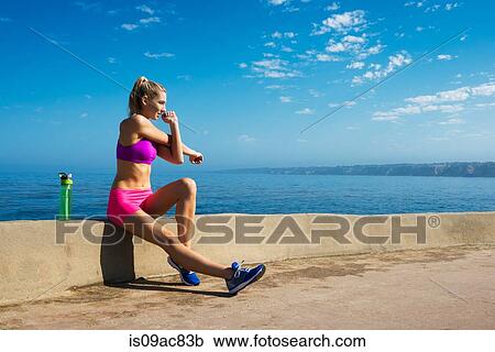 Stock Image - Woman stretching at coast. Fotosearch