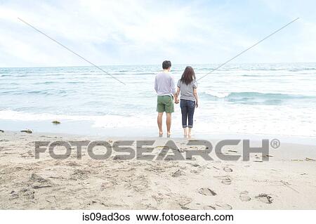 Stock Photograph - Young couple holding hands beach. Fotosearch