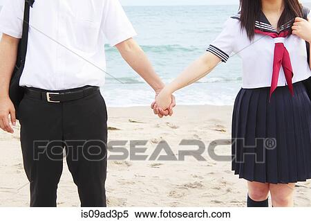 Stock Photography - Young couple holding hands on beach, mid-section. Fotosearch
