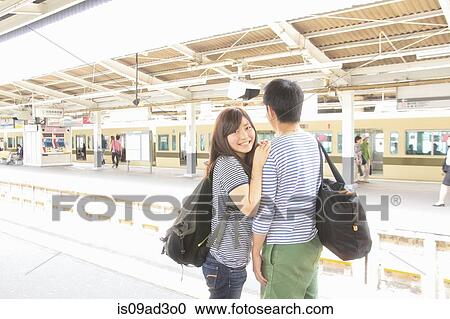 Stock Image - Young couple on platform at train station. Fotosearch