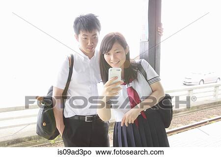 Young couple on railway platform looking at smartphone View Large Photo Image Picture - Young couple on railway platform looking at smartphone. Fotosearch