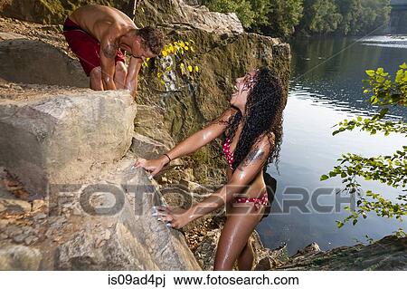 Stock Image - Young couple on rock ledge, Hamburg, Pennsylvania, USA. Fotosearch