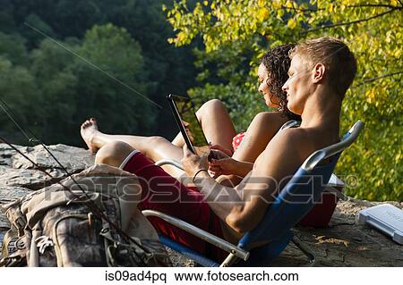 Stock Photography - Young couple relaxing on rock ledge, Hamburg, Pennsylvania, USA. Fotosearch