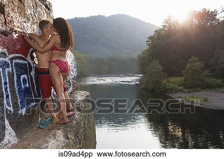Stock Photography - Young couple sharing a kiss on rock ledge, Hamburg, Pennsylvania, USA. Fotosearch