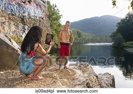Stock Image - Young couple taking portrait on rock ledge, Hamburg, Pennsylvania, USA. Fotosearch