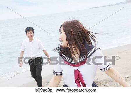 Young couple wearing school uniform running on sandy beach View Large Photo Image Stock Image - Young couple wearing school uniform running on sandy beach. Fotosearch