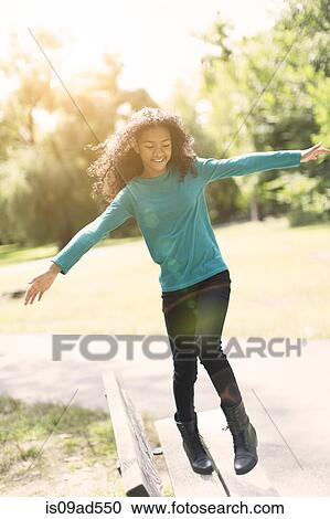 Young girl balancing on bench in park View Large Photo Image Stock Image - Young girl balancing on bench in park. Fotosearch