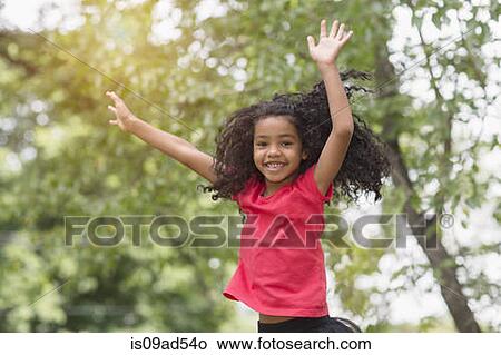 Picture - Young girl jumping and having fun in park. Fotosearch