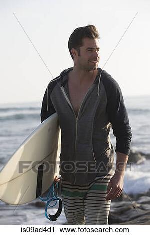 Stock Image - Young man carrying surfboard, San Diego, California, USA. Fotosearch