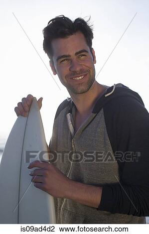 Stock Image - Young man holding surfboard, San Diego, California, USA. Fotosearch