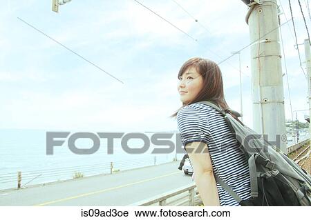 Young woman leaning against fence, looking out to sea View Large Photo Image Stock Image - Young woman leaning against fence, looking out to sea. Fotosearch