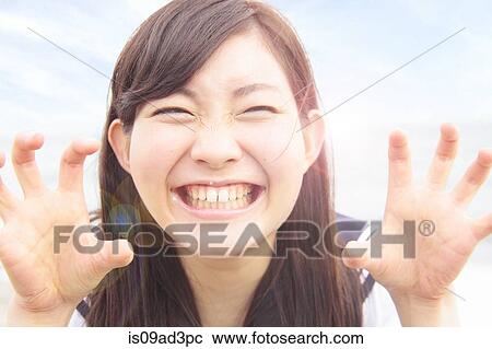 Stock Image - Young woman pulling funny face and hands like claws. Fotosearch