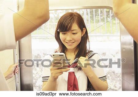 Young woman standing on train using smartphone View Large Photo Image Stock Photography - Young woman standing on train using smartphone. Fotosearch