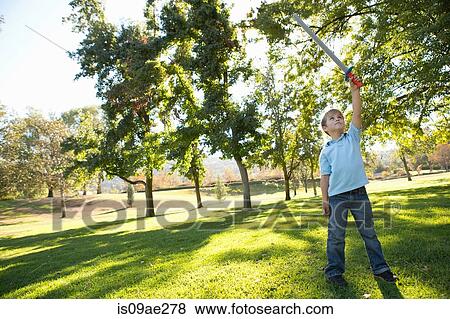 Boy in park raising toy sword in air View Large Photo Image Stock Photo - Boy in park raising toy sword in air. Fotosearch